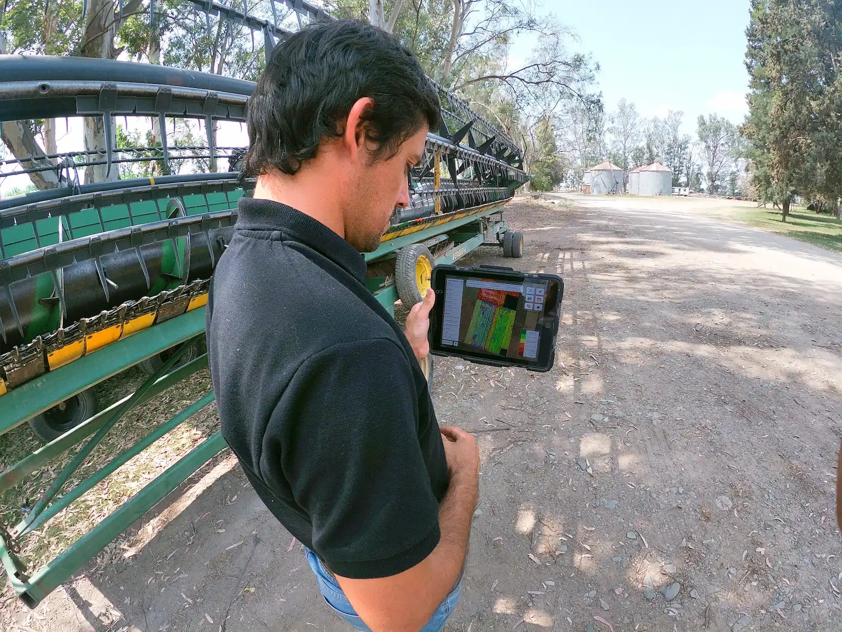 Un asesor con el iPad de FieldView frente a un cabezal de cosecha.